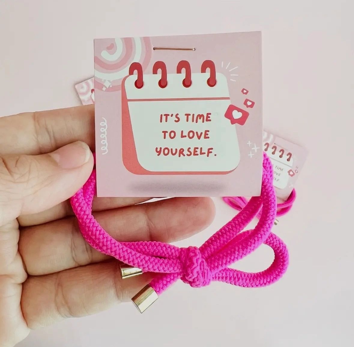 Hand holding pink bracelet and card