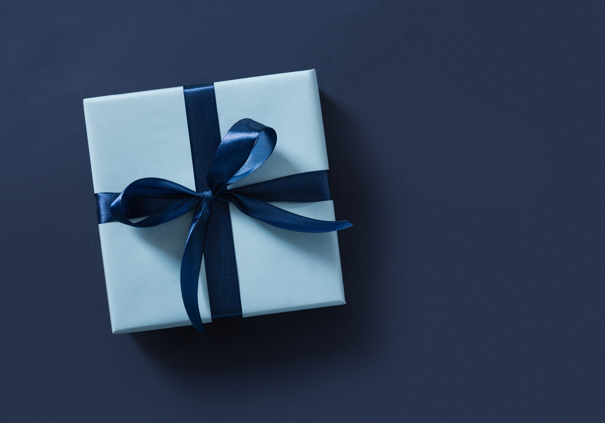 Blue gift box on navy blue background. View from above.